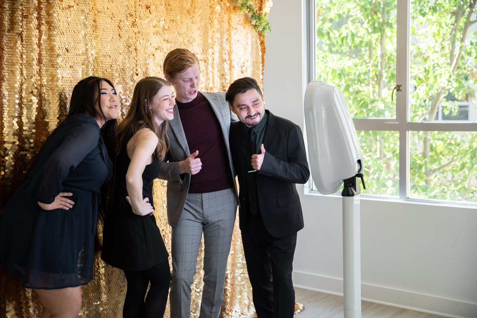 Friends laughing together in front of a gold sequin backdrop at the Mosaic photo booth
