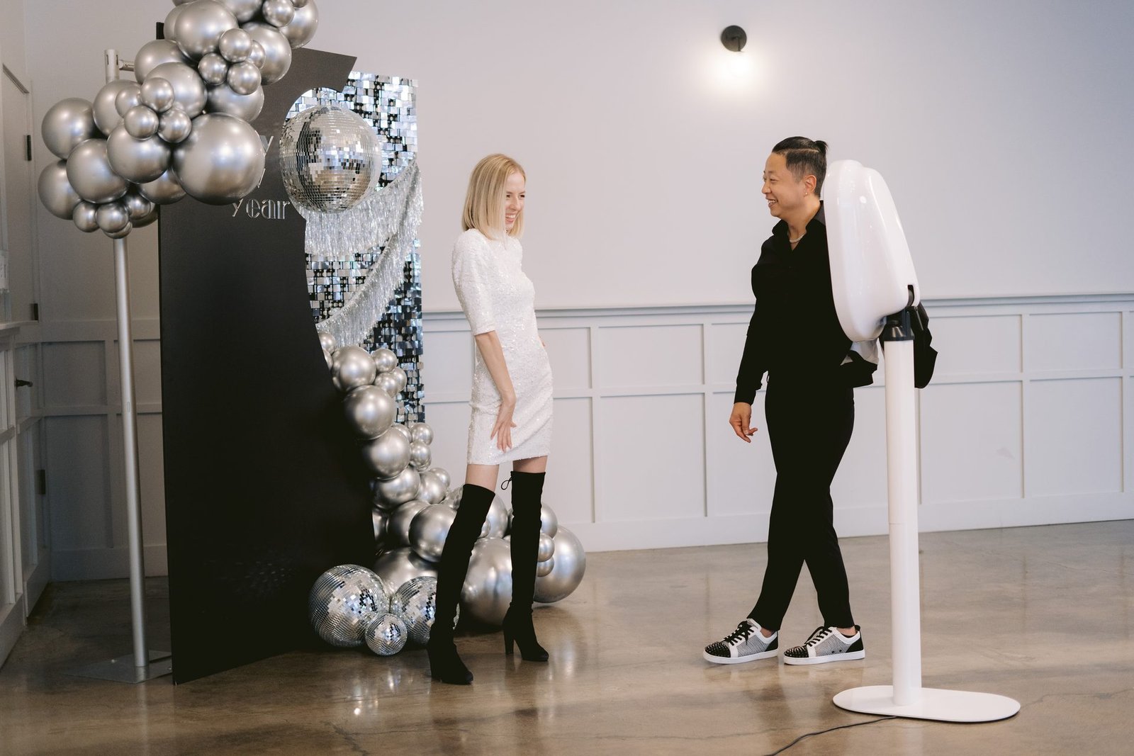 A couple laughing together beside the Mosaic photo booth at a New Year's Eve party